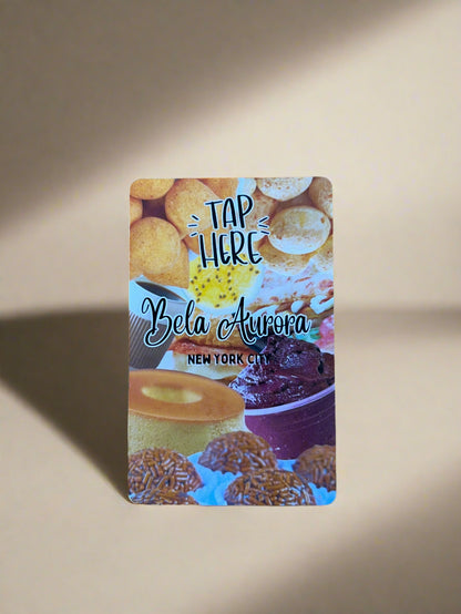 Card with food images and text 'Tap Here' and 'Bela Aurora New York City' on a wooden surface.